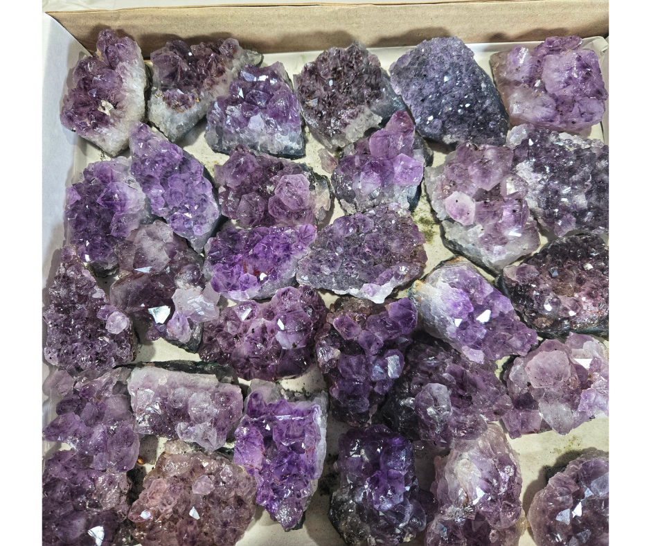 Box of natural amethyst clusters with lavender and deep purple crystal points