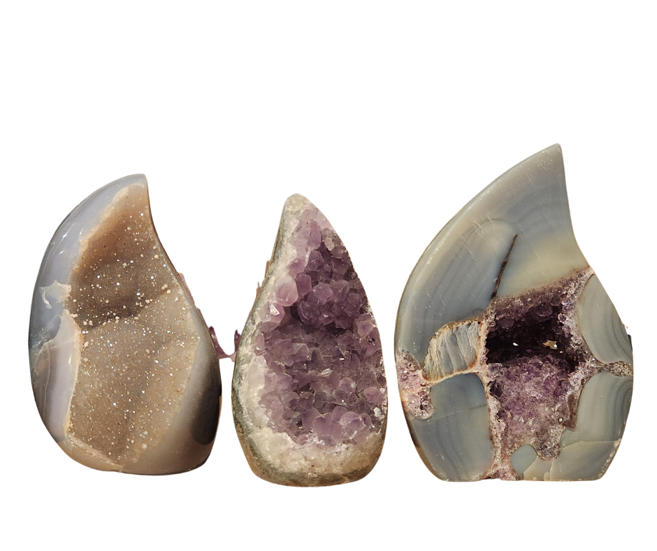 Three polished amethyst flame shapes with exposed sparkling crystal pockets and natural stone banding